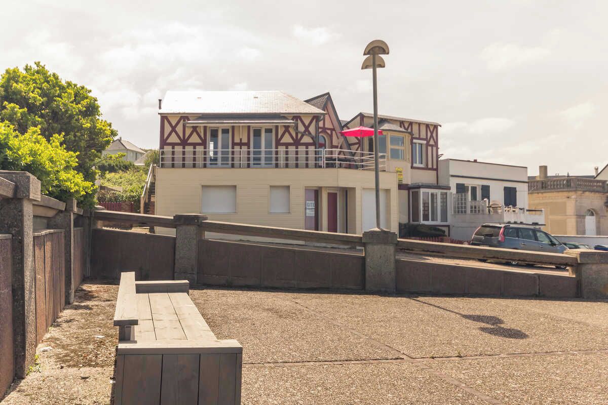 A building with a traditional architectural style, featuring a balcony and a red umbrella.