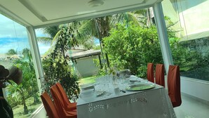 Un comedor moderno con una mesa de vidrio, sillas rojas y vistas a exuberante vegetación.