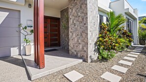 A modern building with a stone facade, a wooden door, and a gravel pathway leading to the entrance.