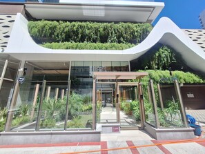 A modern building with a glass entrance, a green rooftop garden, and a sign indicating '2050'. - Luxury apartment, (150m) from the sea and wonderful leisure for the family. (Praia da Costa Vila Velha)
