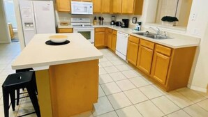 A kitchen with wooden cabinets, a white countertop, a sink, and a refrigerator. - Bella Vida Home (Kissimmee)
