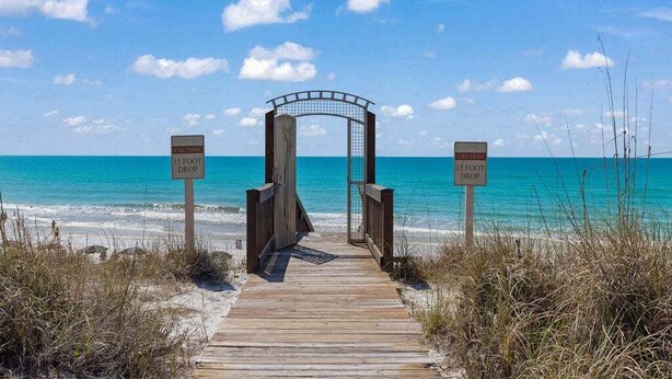A wooden boardwalk leading to a beach with a sign indicating a 15-foot drop. - Spacious 3BR Condo | Walk to Beach | Pool, Hot Tub & Balcony Views (Blue Mountain Beach)