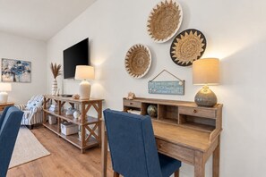 A modern living room with a wooden coffee table, two blue chairs, a TV mounted on the wall, and decorative wall art. - Redfish Village M2-329 - 3BR/3BA Corner Condo - Sleeps 12 - Community Pool (Blue Mountain Beach)