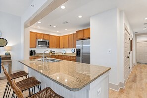 Una cocina moderna con encimeras de granito, electrodomésticos de acero inoxidable y armarios de madera.