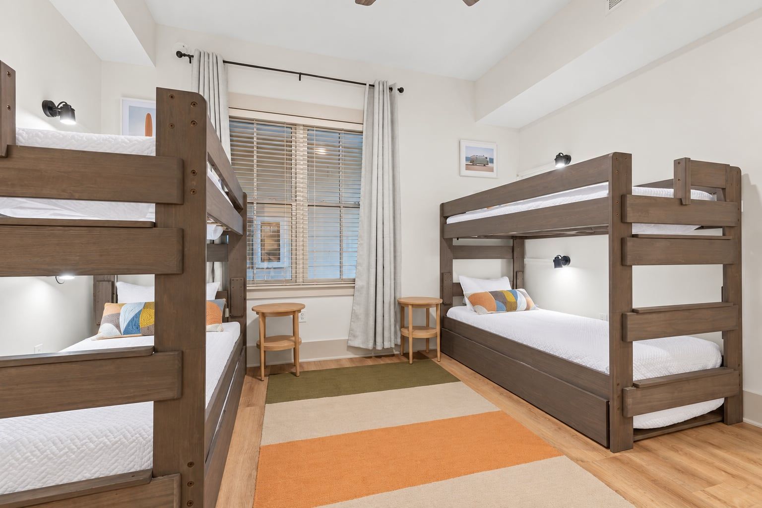 A room with bunk beds, a small table, and a window with curtains.