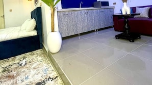 Un saló modern amb un sofà, una zona de menjador amb un taulell blau i una planta gran en test.