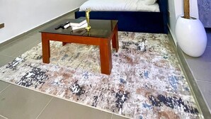 Un saló modern amb un sofà, una taula de centre, un televisor fixat a la paret i una planta en test.