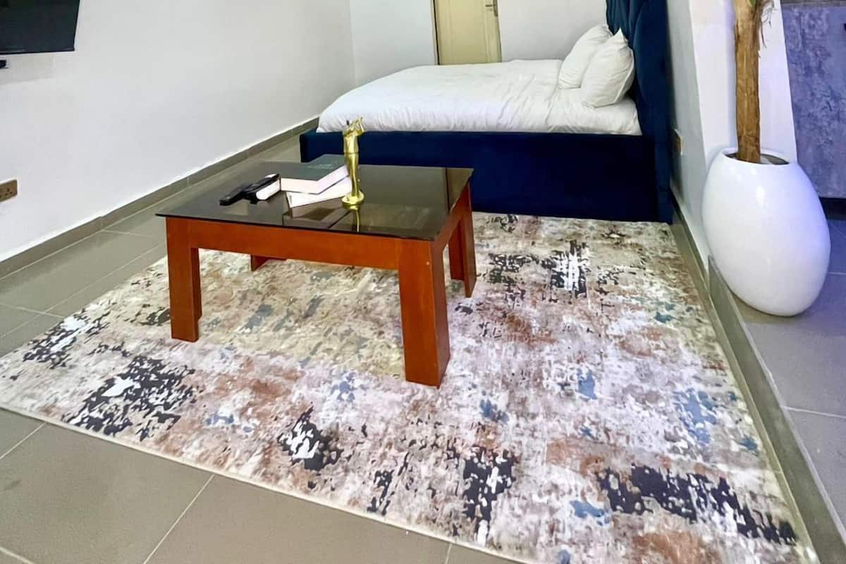 Una sala de estar moderna con un sofá, una mesa de centro, un televisor montado en la pared y una planta en maceta.