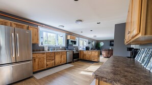 Una cocina moderna con armarios de madera, electrodomésticos de acero inoxidable y un amplio ventanal que proporciona luz natural.