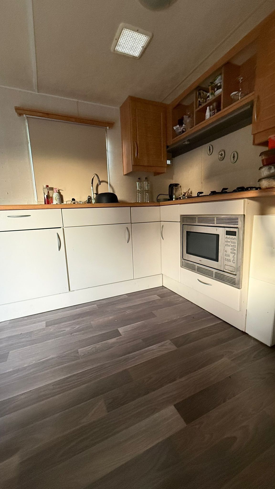 A kitchen with white cabinets, a microwave, and a wooden countertop.