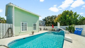 A swimming pool with a white deck, a light green building, and a white picket fence. - "Casa Verde" - Private Pool - West End (Panama City Beach)