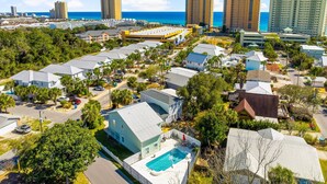 A coastal residential area with a variety of houses, some with swimming pools, and several high-rise buildings in the background. - "Casa Verde" - Private Pool - West End (Panama City Beach)