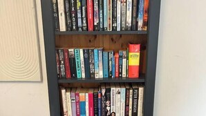 A bookshelf with various books and a small box of board games.