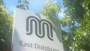 A sign for East Didsbury with a train symbol.