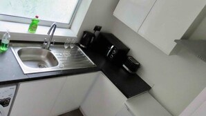 A kitchen with a stainless steel sink, a window, and a black countertop.