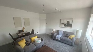 A living room with two sofas, a coffee table, a dining table with chairs, and a painting on the wall.