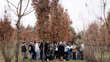A group of people gathered outdoors in a natural setting with trees and shrubs.