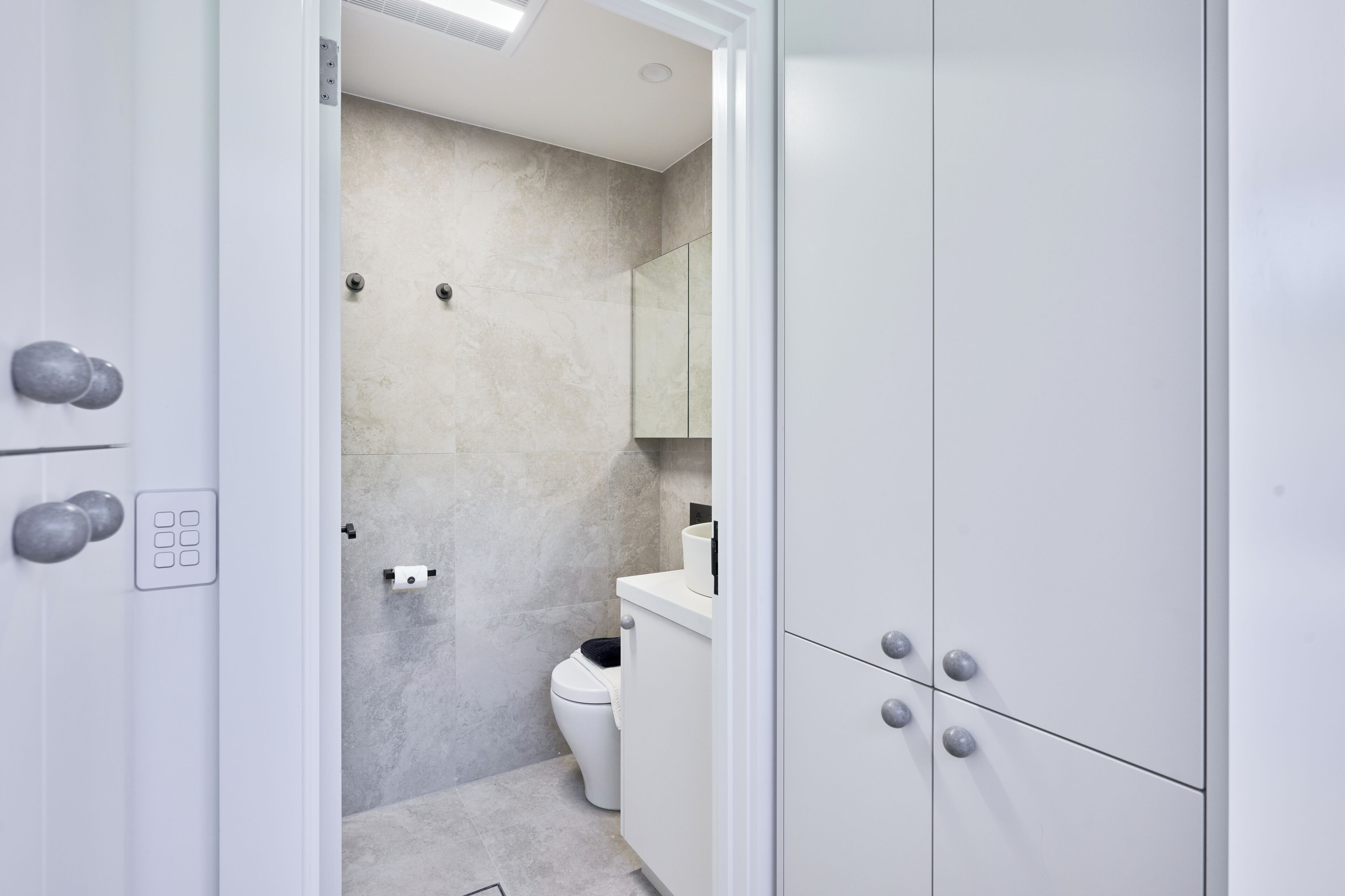 A modern bathroom with a toilet, a sink, and a mirror.