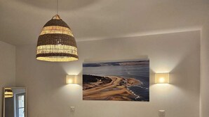 A bedroom with a large bed, a hanging lamp, a wall-mounted picture, and bedside tables with lamps. - Duplex flat for 2 people with terrace and parking (Bordeaux)