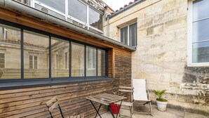 An outdoor seating area with wooden benches and a table, a whiteboard, and a potted plant. - Duplex flat for 2 people with terrace and parking (Bordeaux)