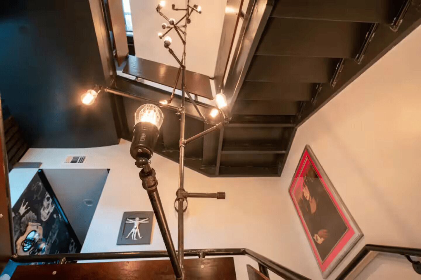 A staircase with a modern light fixture and artwork on the walls.
