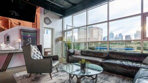 Una sala moderna con un sofá de cuero, una mesa de centro de vidrio y vistas de la ciudad a través de amplios ventanales.