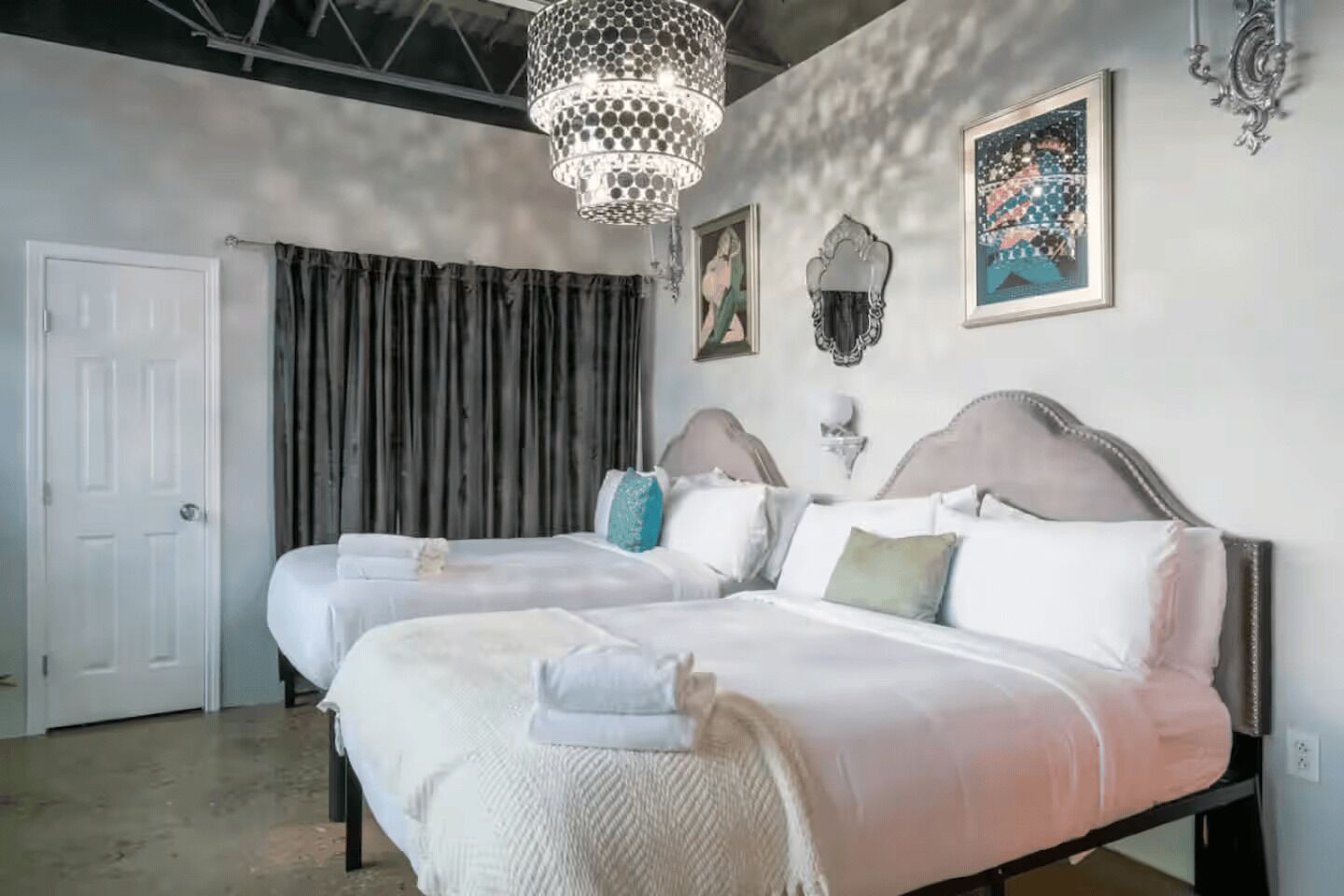 Een tweepersoonsbed met hoofdbord, een hanglamp en een ingelijst schilderij aan de muur.