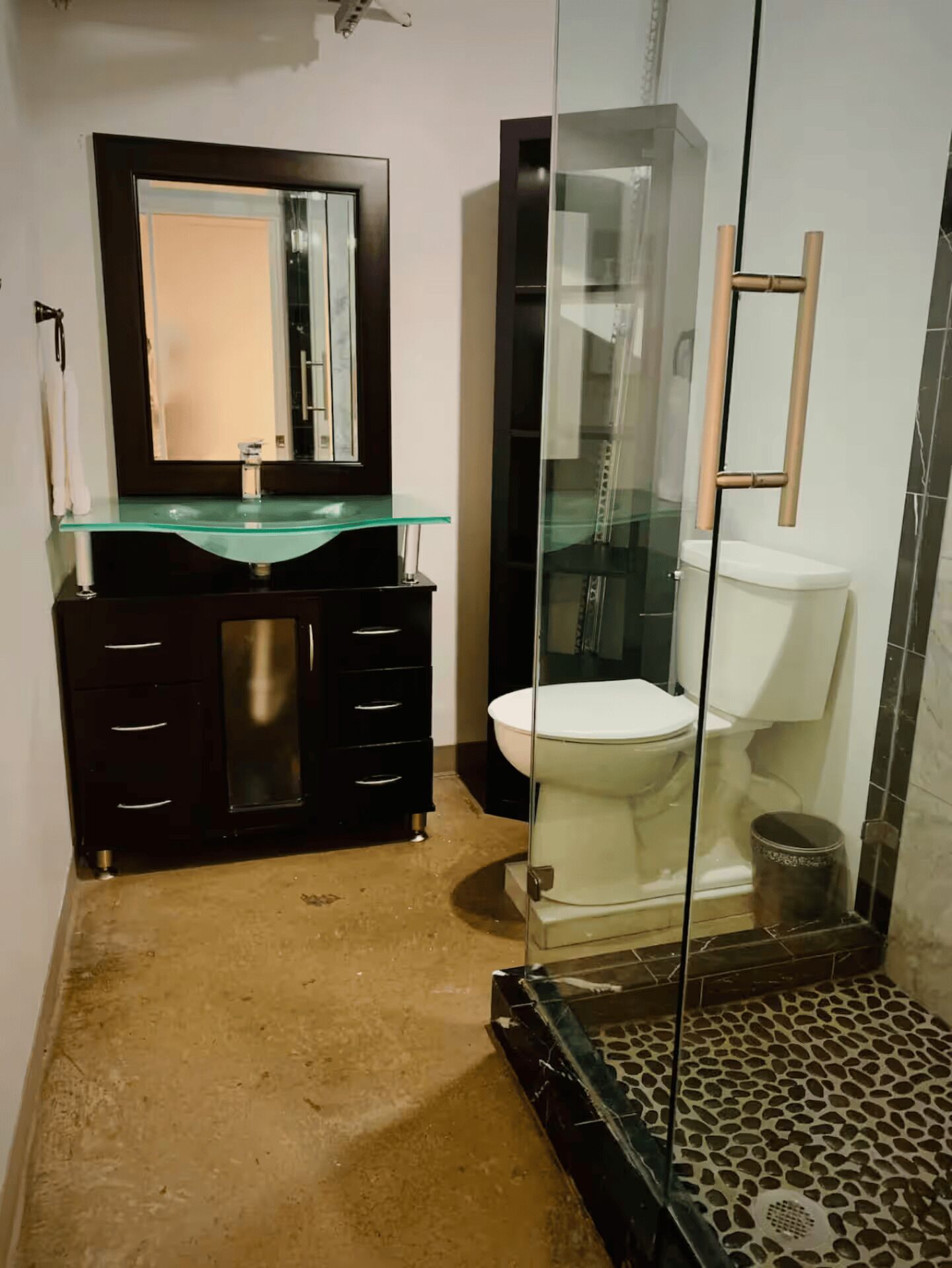 A modern bathroom with a glass sink, dark wooden vanity, and a glass-enclosed shower area.