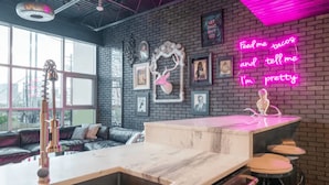 Una cocina moderna con barra, un letrero de neón y una pared de ladrillo decorada con cuadros.