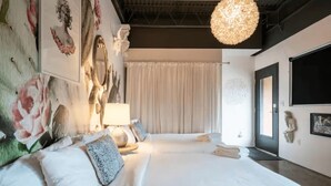 Un dormitorio moderno con una cama grande, una mesita de noche con lámpara y obras de arte en las paredes.