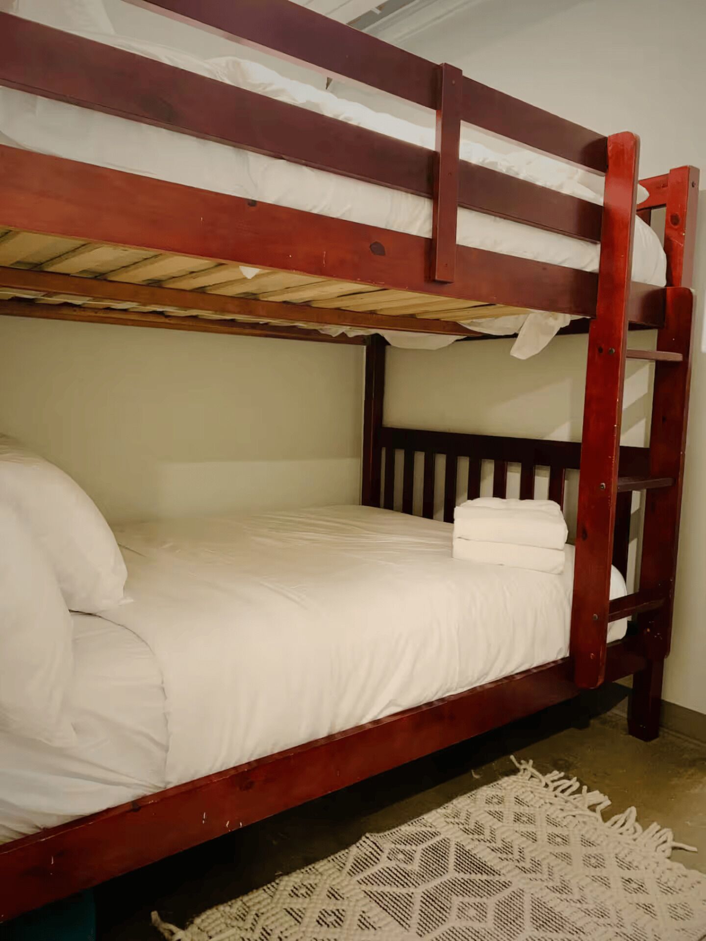 A bunk bed with white bedding and a wooden frame.