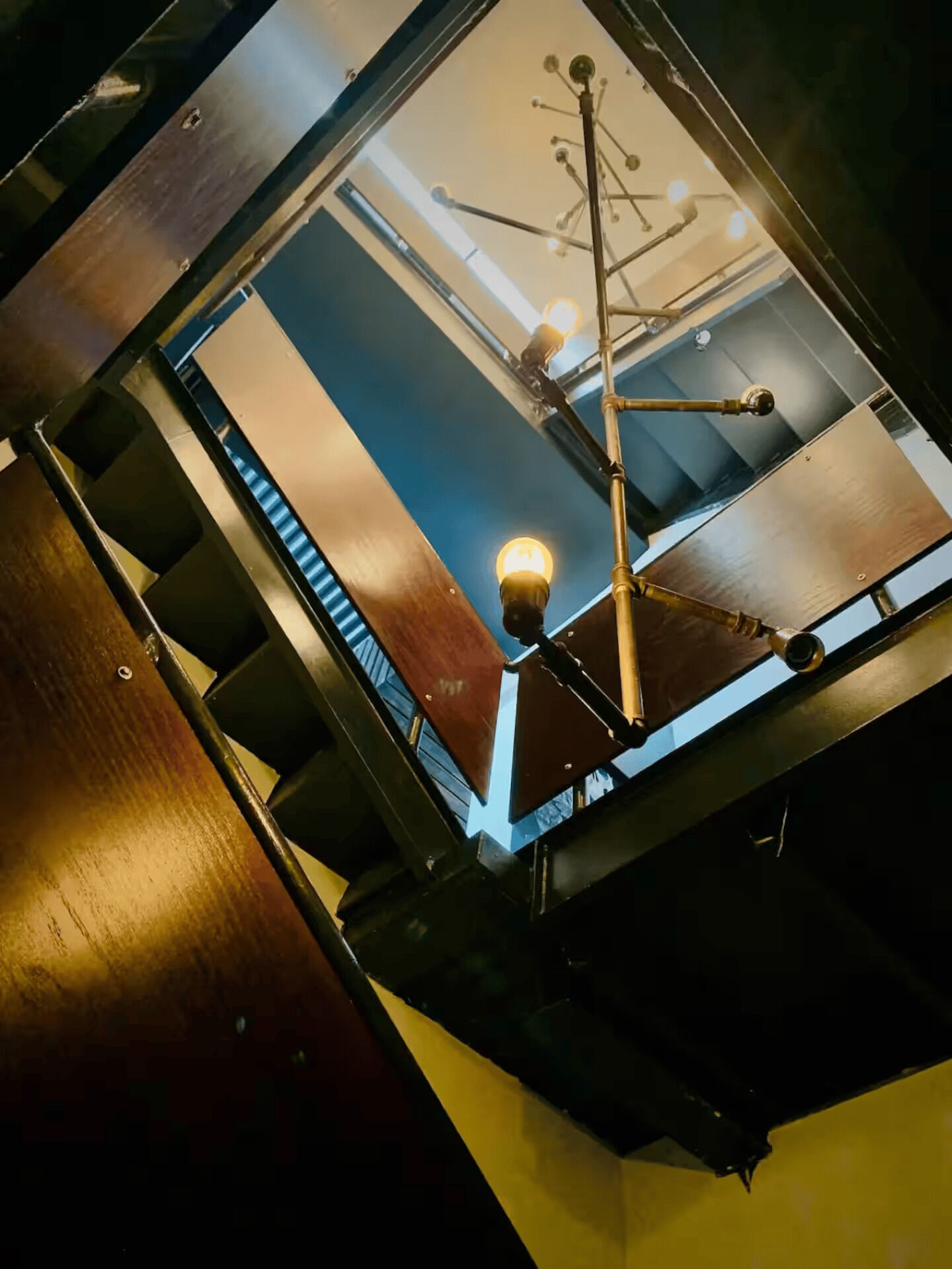 Vista de una habitación con suelo de madera, techo con lámpara y ventana con persianas.