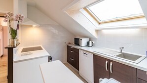 A compact kitchen with white and dark brown cabinetry, a microwave, a kettle, and a dishwasher. A skylight provides natural light. - MAISON MARMILLONS - CANOPEE (AIX LES BAINS)