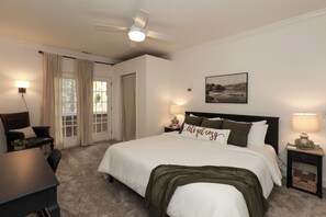 Une chambre d’hôtel équipée d’un lit, d’un bureau, d’une chaise, d’un ventilateur de plafond et d’une fenêtre avec des rideaux.