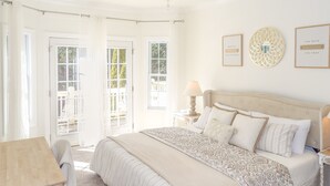 A bedroom with a large bed, a desk, and a chair. There are two doors leading to a balcony. - 4BR Innsbruck | Closest to Helen | Private Hot Tub | Pool, Tennis & Pickleball (Helen)