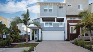 A two-story residential building with a garage, a balcony, and a small porch area.