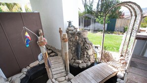 Ein Garten mit einer Holzbrücke, einer Vogel-Skulptur und einer Steinmauer.