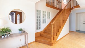 Eine Treppe mit hölzernen Geländern und einer Zwischenebene mit Spiegel und Topfpflanzen.