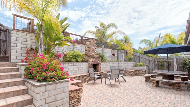 A patio with stone steps, a fire pit, outdoor furniture, and a wooden fence.