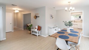 Una cocina moderna con armarios blancos, encimera de madera y una lámpara colgante.