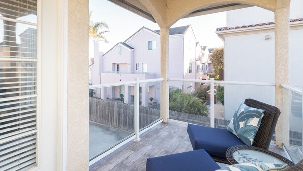 Un balcon donnant sur les maisons voisines, une terrasse en bois et du mobilier d’extérieur.