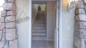Un mur de pierre avec une pancarte indiquant « RELAX », un escalier et un luminaire fixé au mur.
