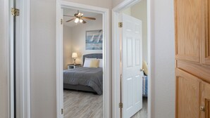 Une chambre à coucher avec un lit, une table de chevet, une lampe et un ventilateur de plafond.