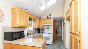 A kitchen with wooden cabinets, a microwave, a stove, and a sink.