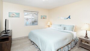 A bedroom with a bed, a TV, and artwork on the walls.