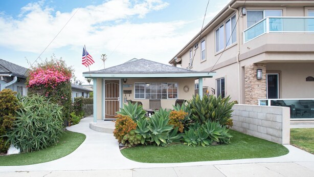 A two-story house with a well-maintained lawn, a small porch, and a flag.
