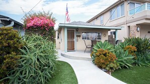 A residential house with a front porch, a flag, and well-maintained landscaping.