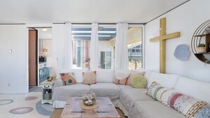 A modern living room with a large sectional sofa, a coffee table, and a view through large windows.