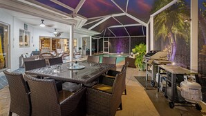 An outdoor patio area with a pool, dining table, and chairs.