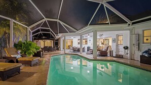 An indoor swimming pool with lounge chairs and a covered patio area.